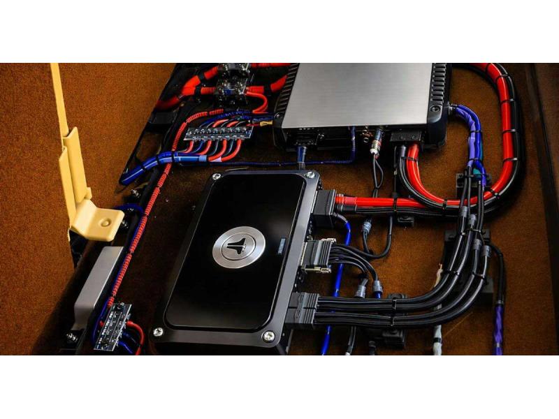 Автомобільний підсилювач і сабвуфер у багажнику з підключеними силовими кабелями та якісною проводкою для автозвуку